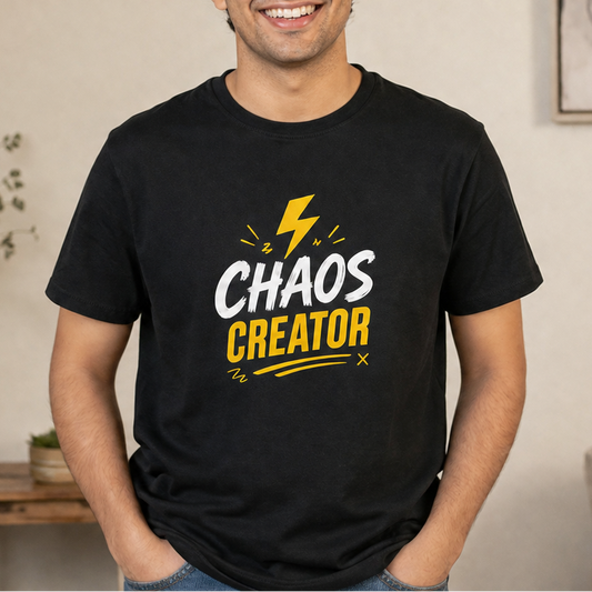 A man wearing a black short-sleeve t-shirt with a graphic print that reads 'CHAOS CREATOR' in white and yellow text with a yellow lightning bolt, set against a blurred indoor background.